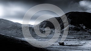 Monochrome shot of an isolated hut amidst a valley