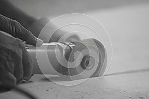 Monochrome toned image of angle grinder cutting concrete with hands of heavy industry worker.