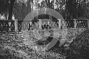 Monochrome view of old stone bridge over river at park
