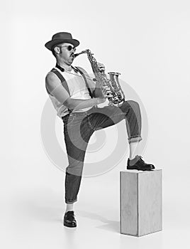 Monochrome. Young stylish man playing saxophone. Live performance. Concept of creativity, retro fashion style, music