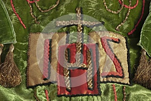 Monogram or symbol for Jesus with a gold cross at top embroidered on Christian vestment. photo