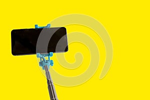 Monopod for selfie with smart phone. Selfie stick with smartphone isolated on yellow background