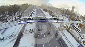 Monorail train passes over a four-lane road in the photo