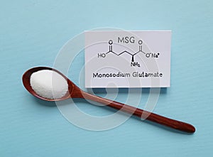 Monosodium glutamate (MSG) chemical formula with spoonful of white glutamate powder. Sodium salt of glutamic acid