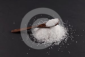 Monosodium glutamate Msg in a wooden spoon on a dark background. Food supplement E621. Taste seasoning to enhance the food