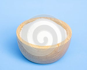 Monosodium glutamate in wood bowl on light blue background