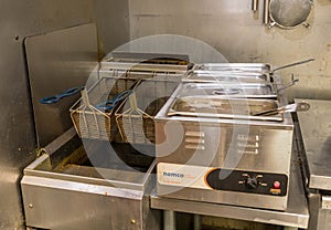 A deep fryer machine in the kitchen of a pizza shop