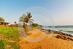 Monrovia, Liberia - April 23, 2019: Beach with red sand and black rocks with a blue sky in Congo Town, Monrovia, Liberia