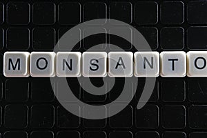 Monsanto title text word crossword. Alphabet letter blocks game texture background. White alphabetical letters on black