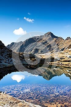 Mont Mars reflected in the Rosso lake in a sunny autumn day