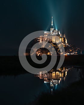 Mont-Saint-Michel by night, illuminated and reflection above the sea, France, Europe.