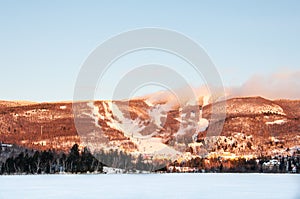 Winter landscape of Ski Resort with Frozen Lake, Ski Slopes and Blue Sky - Mont-Tremblant, Quebec, Canada