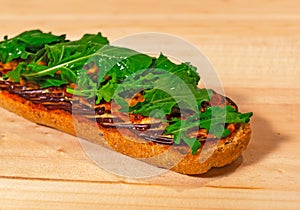 Montadito of arugula, roasted eggplant, tomato and homemade bread open on top of raw wood - Montadito de rÃÂºgula, berenjenas photo