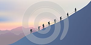 Roped mountaineers climb the side of a mountain as they walk along a ridge at sunset. photo