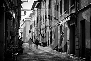 MONTAIONE, ITALY - SEPTEMBER 10, 2023 - An elderly couple walking through an empty alley of Montaione in the Tuscany in the early