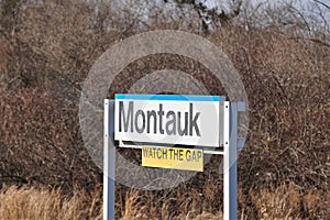 Montauk railroad station sign with posted Watch The Gap warning in yellow