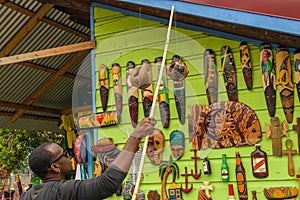 Young male vendor selling wall art wood carvings at craft market