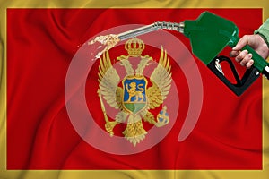 MONTENEGRO flag Close-up shot on waving background texture with Fuel pump nozzle in hand. The concept of design solutions. 3d