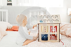 Montessori and Bizibord. A small child plays with a wooden house developing