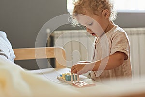 Montessori learning materials. Active playtime fun. Happy childhood memories. Toddler little blonde baby girl palying with wooden