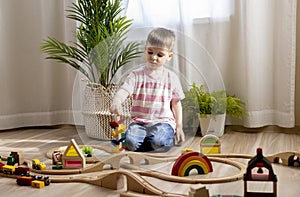 Montessori material. Boy builds a wooden railroad on the floor. Imaginary world of childhood