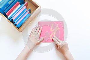 Montessori material. Children`s hands. The study of letter and words. Rough alphabet occupation