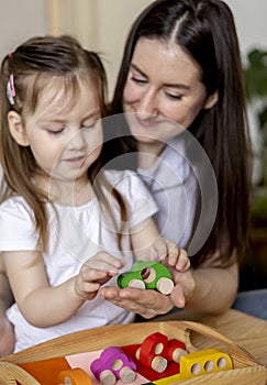 Montessori material. Mom and daughter learn colors. Wooden toy cars