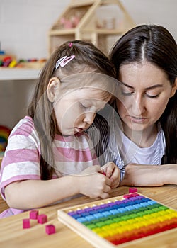 Montessori material. Mom and daughter are studying the colors of the rainbow. Wooden colored cubes