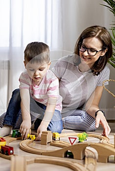 Montessori material. Mom and son learn transport through the game. Wooden railroad
