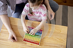 Montessori material. Top view of the hands of a girl and her mother learning the number at home school