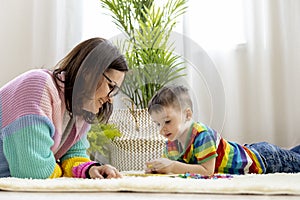 Montessori material. Woman and a boy study at a home school. Mom and son in rainbow clothes