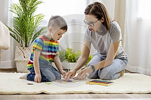 Montessori material. Woman and a boy study at a home school. Mom and son in rainbow clothes