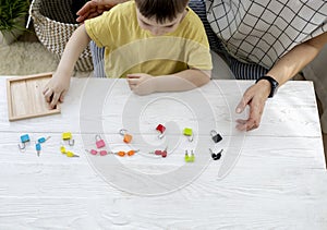 Montessori material. Woman and a boy are studying a puzzle with keys and locks
