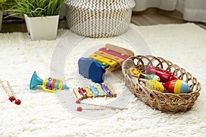 Montessori material. Wooden musical instruments in a wicker basket on the floor