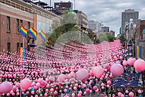 Montreal, CA - 14 August 2016: Pink balls across Rue Sainte Catherine in the Gay Village of Montreal with gay rainbow flags and m