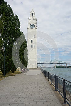 Montreal Clock Tower and Jacques Cartier Bridge at Old Port, Montreal, Canada. Background is a blue cloudy sky.