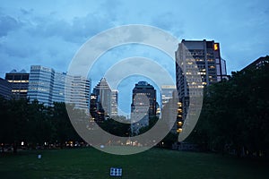 Montreal, QC, Canada - 7-15-2021: A skyline of Downtown, Sherbrooke street at the twilight blue hour. Foreground is McGill