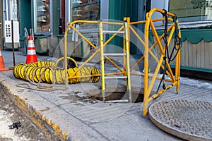 Manhole opened with ladder going down and safety rails