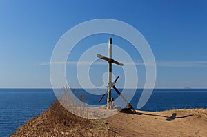 Monument in the form of a wooden cross and an old anchor, standing on a cliff on the edge of Cape Tobizin, Vladivo