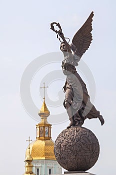 Monument to goddess Nike on sphere against cupolas of the church.