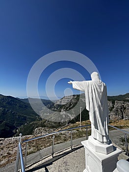 Monument to Jesus Christ and a large cross under the blue sky, above the Cievna canyon. Tourist route on the way to Grlo