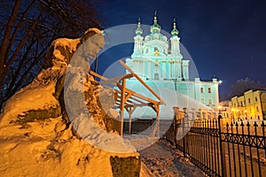 The monument to Taras Shevchenko in the snow and St. Andrew`s Church on a hill at night. Andriyivskyy Descen uzviz. Kyiv photo