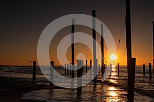 Monumental wooden poles, including a swing set, in the sea during a lovely sunset in the Netherlands