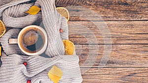 Autumn or Fall composition. Fall leaves, orange chips, hot steaming cup of coffee and a cozy grey sweater on wooden