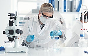 Mood Obtaining results. an attractive female scientist pouring a liquid into a beaker in a laboratory with her colleague