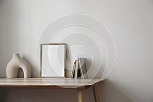 Moody artistic living room interior, home office. Empty wooden picture frame, poster mockup on wooden table. Old books