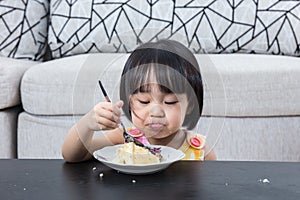 Moody Asian Chinese little girl eating birthday cheese cake