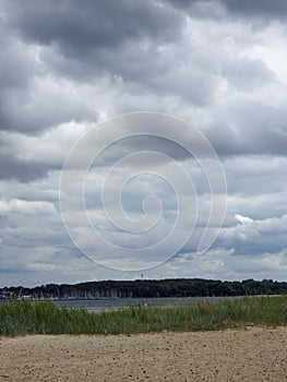 A moody coastal scene: dark clouds loom over the Baltic Sea, casting a shadow on the serene beach below, adding an air of mystery