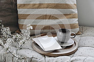 Moody epring interior still life. Cup of coffee, tea on wooden tray. Blank greeting card, invitation mockup. Blossoming