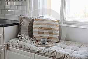 Moody epring interior still life. Cup of coffee, tea on wooden tray. Blossoming cherry plum tree branches. Sitting bench